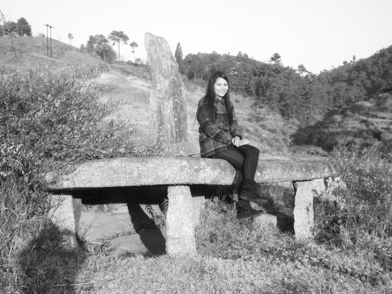 Black and White photograph of a woman sitting on part of a monolith