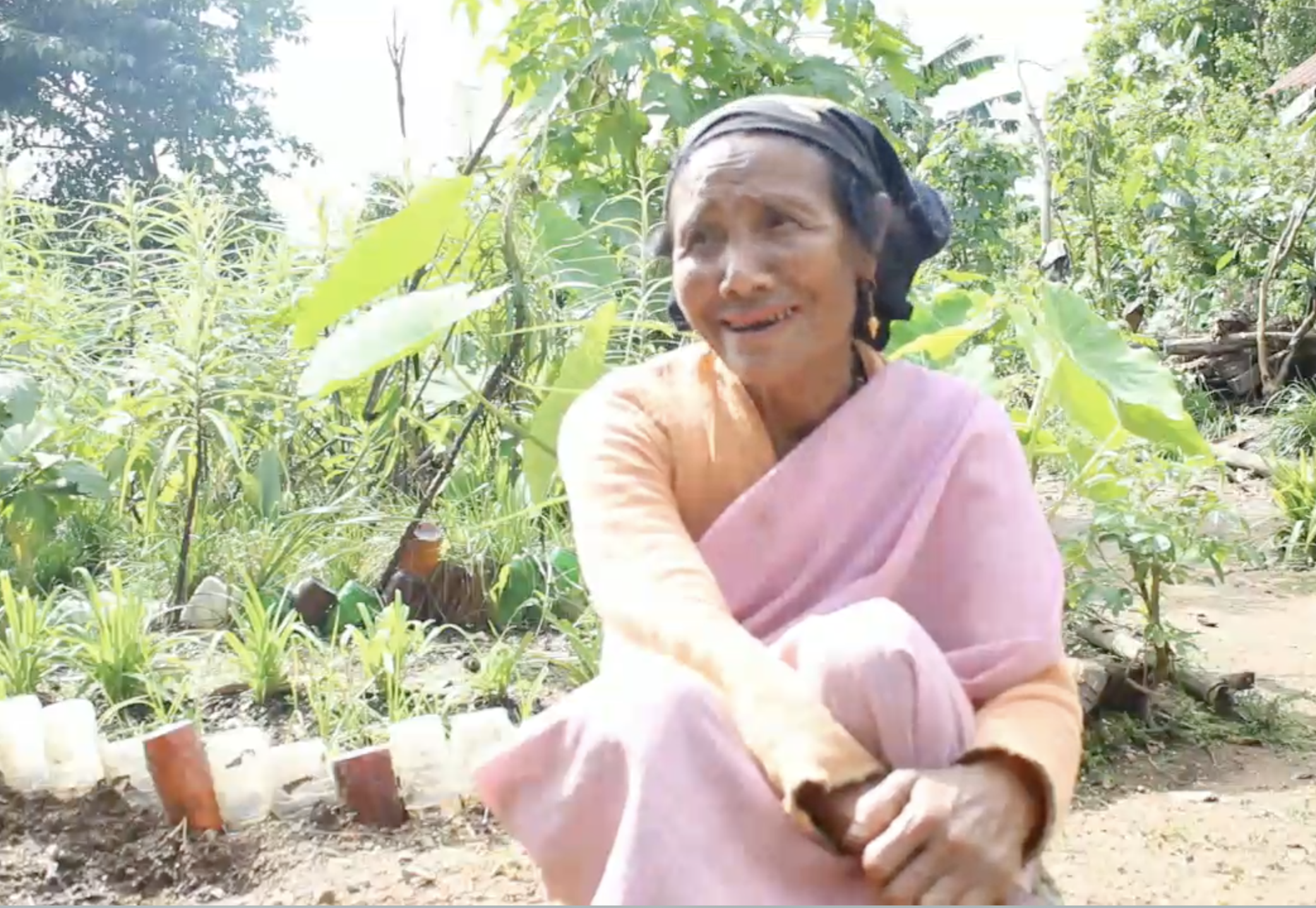 A woman sitting in front of her garden